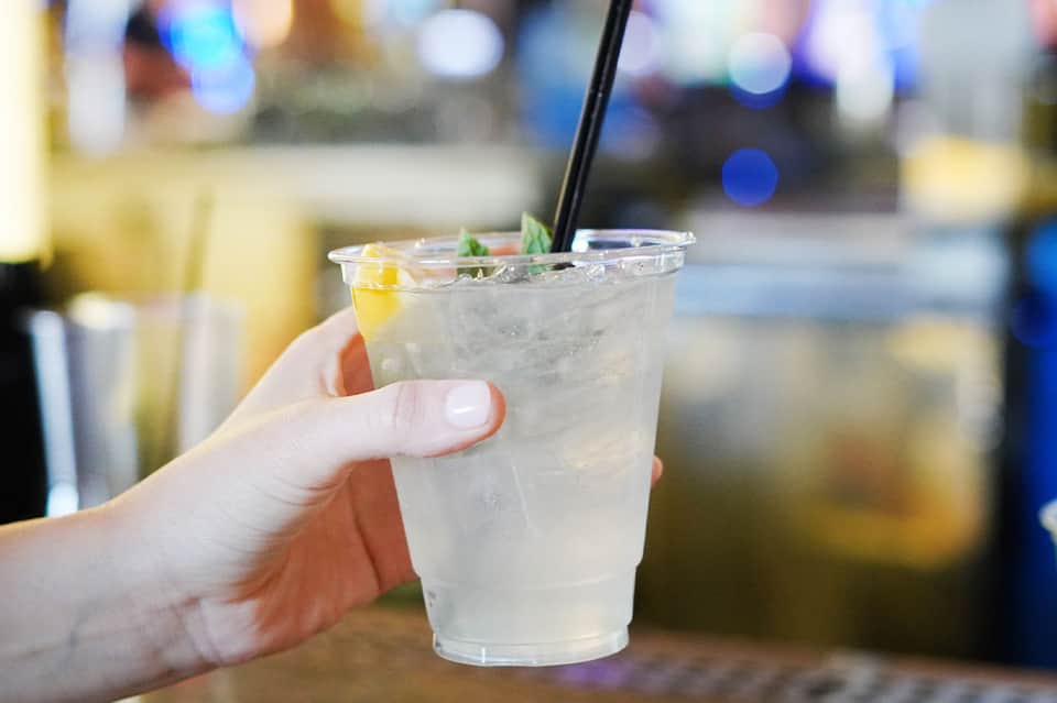 Hand holding refreshing cocktail with lemon garnish at poolside bar