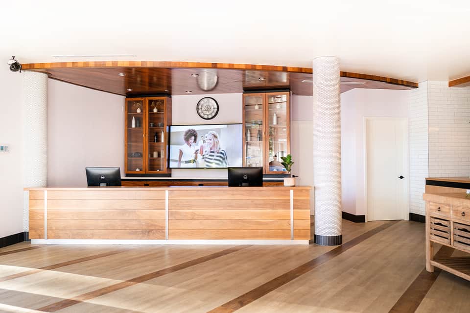 Modern hotel reception desk with wooden finishes, white columns, and contemporary art