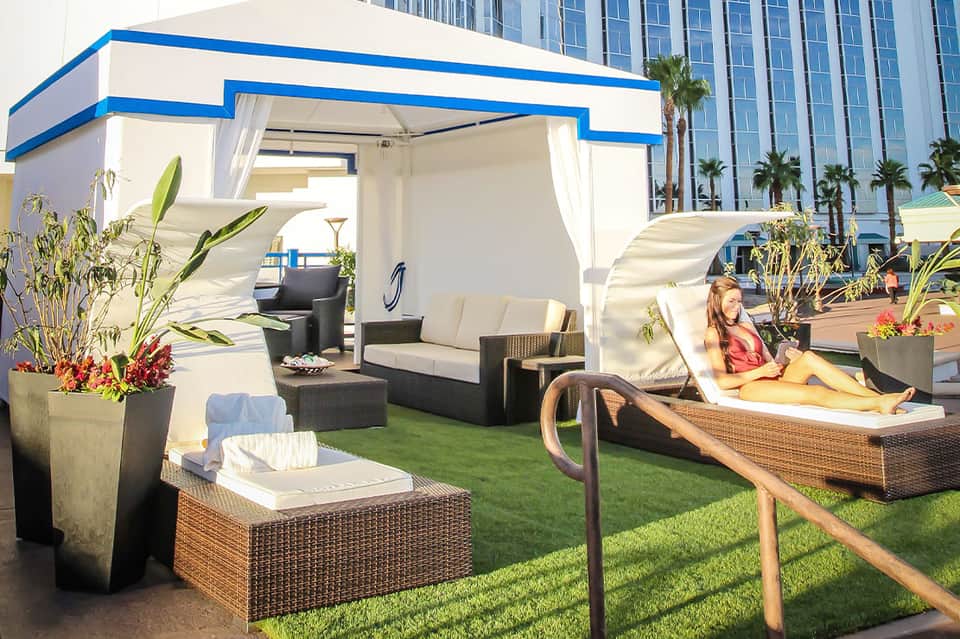Rooftop terrace with cabanas, lounge chairs, and artificial turf overlooking urban skyline