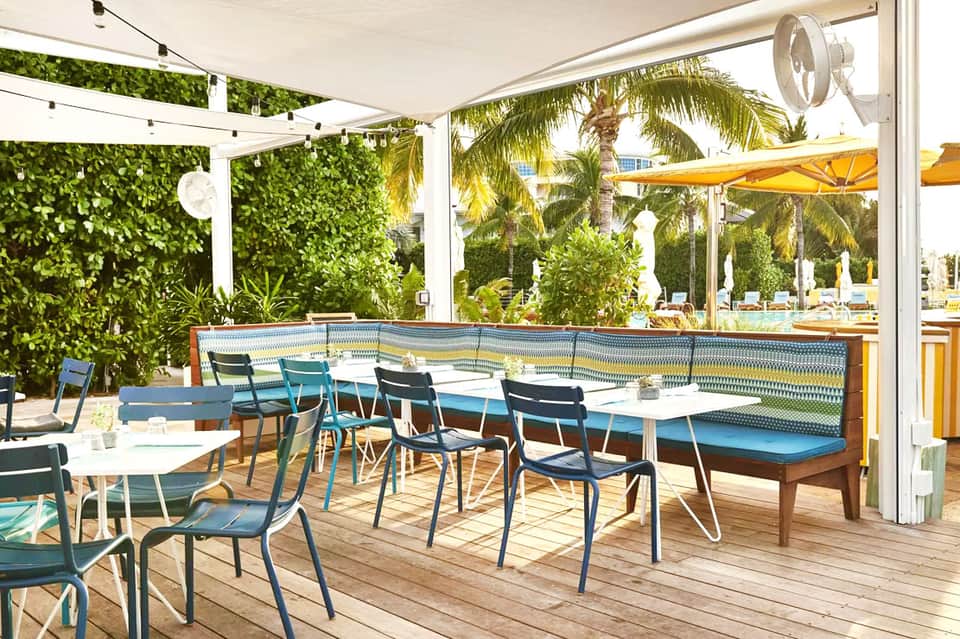 Covered poolside dining terrace with modern furniture and tropical plants