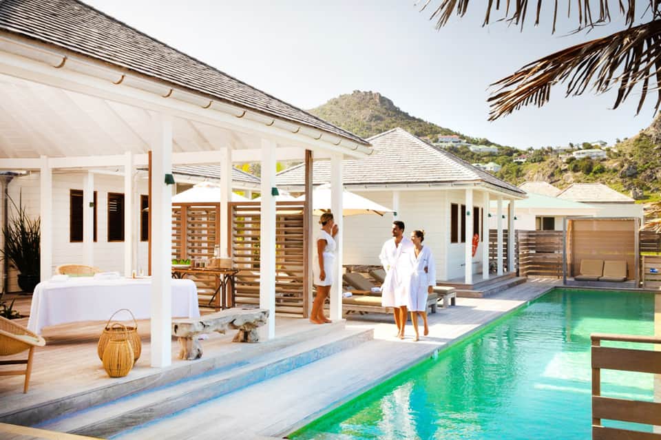 Luxury beachfront resort with white cabanas, emerald pool, and mountain backdrop