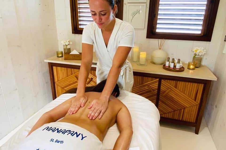 Spa therapist performing massage treatment in serene wellness room with candles and wooden furnishings