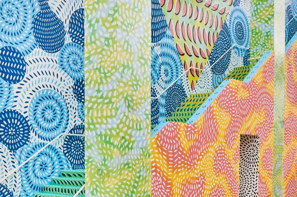 Colorful fabric display featuring intricate blue, green, yellow, and coral geometric patterns