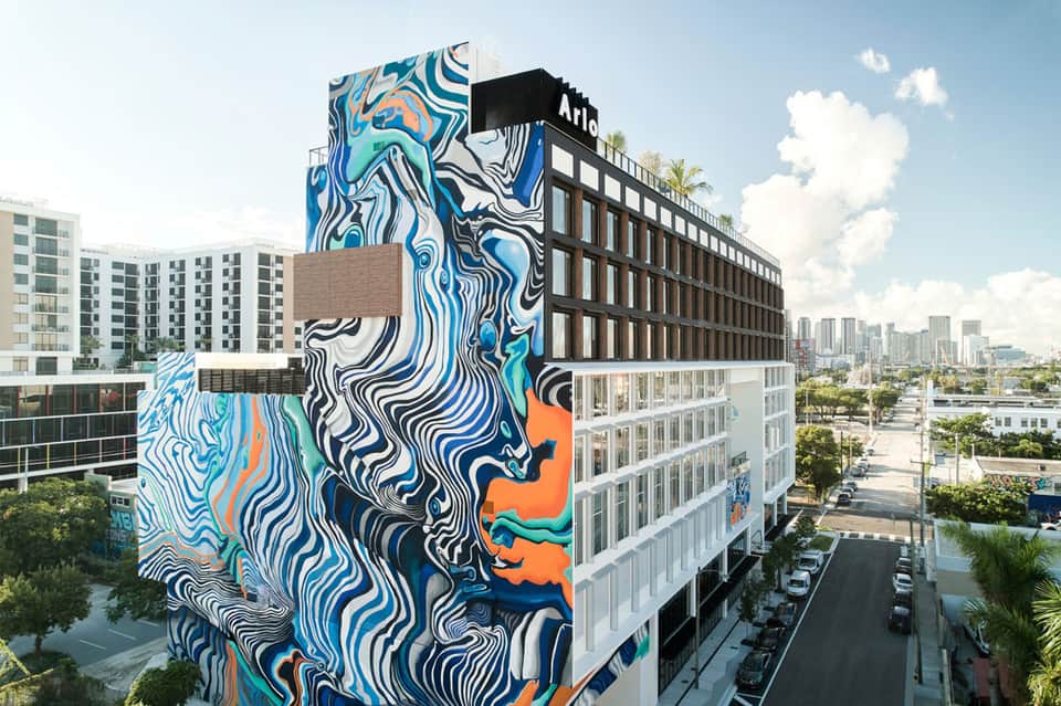 Modern urban hotel building with vibrant blue and orange mural art on exterior facade