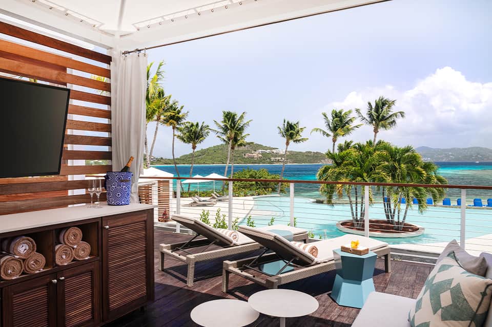 Resort terrace with pool view, wooden privacy screen, and ocean vista beyond