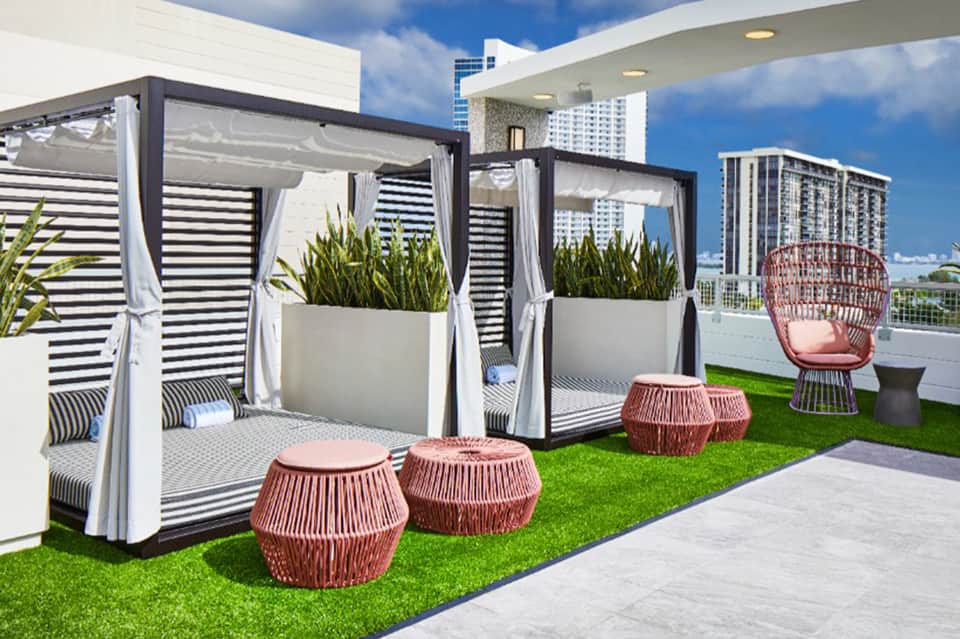 Rooftop lounge with striped cabanas, potted plants, and city skyline views