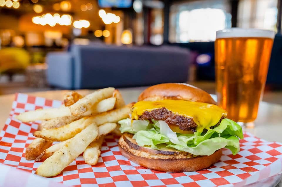 Gourmet burger and fries served on red checkered paper with beer