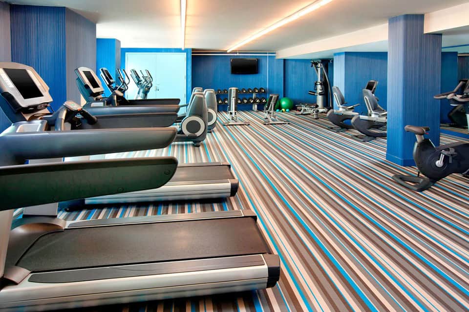 Contemporary fitness center with blue accent walls, multiple treadmills, and exercise equipment