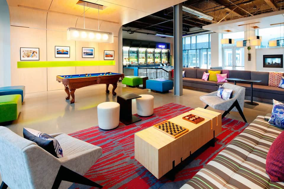 Modern recreation lounge with pool table, colorful seating, games, bar, and contemporary furnishings