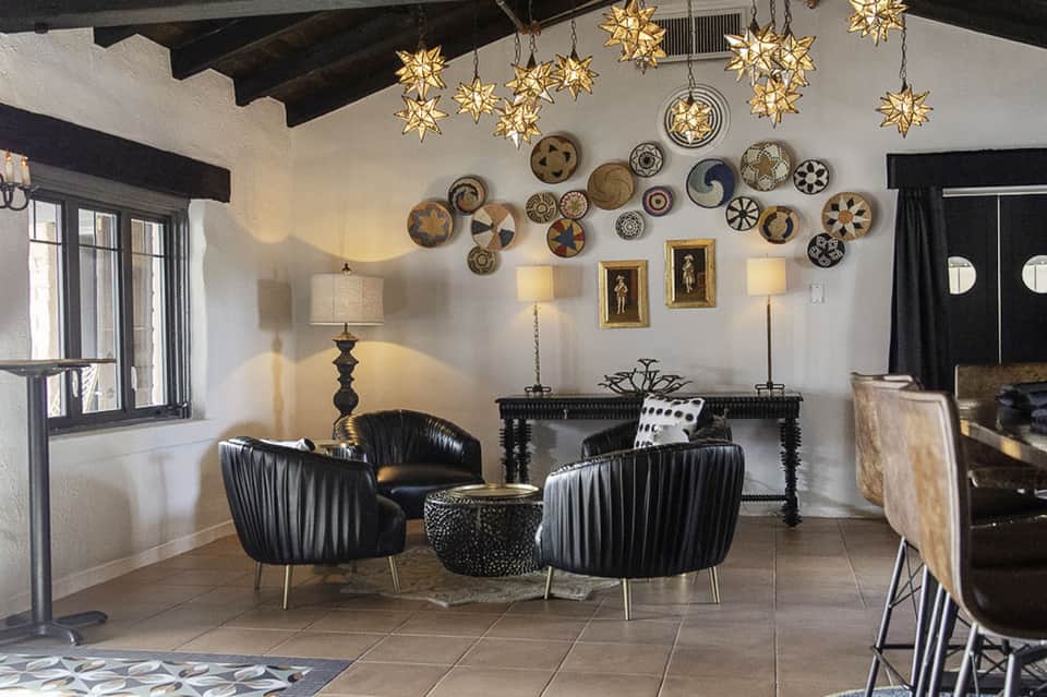 Modern lounge area with black leather chairs, decorative plates, hanging gold stars, and pendant lighting