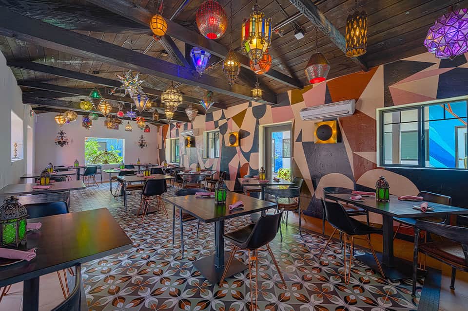 Vibrant restaurant interior with colorful Moroccan lanterns, geometric wall art, and dining tables