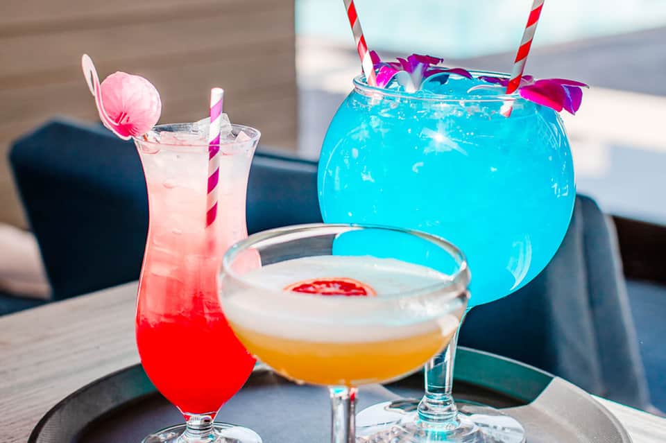 Vibrant tropical cocktails including bright blue and pink drinks with decorative garnishes