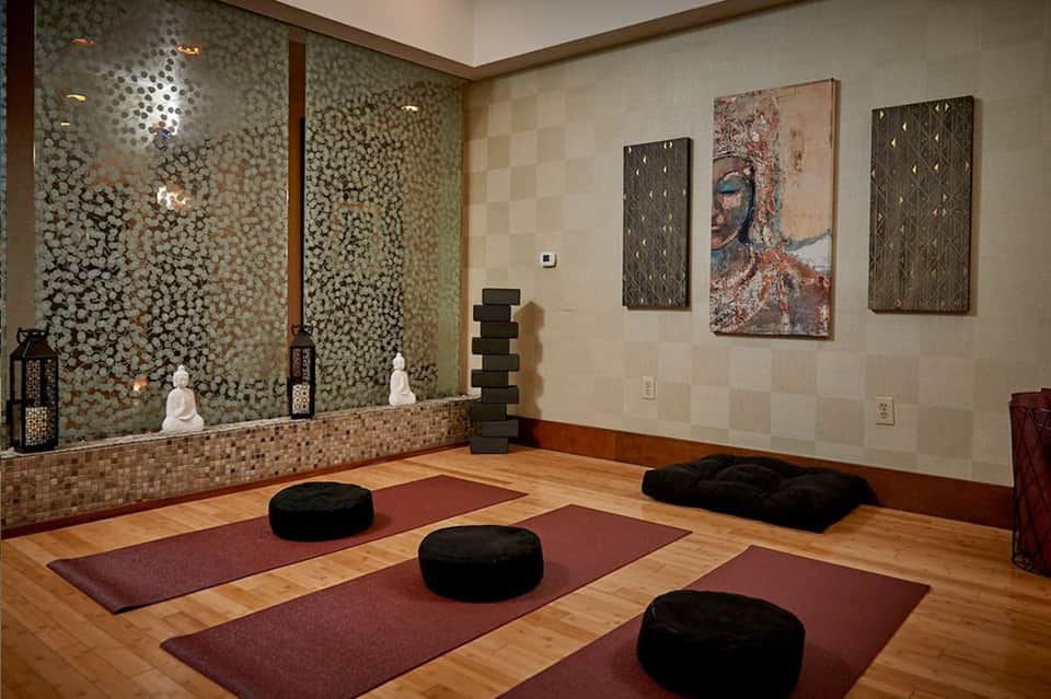 Yoga and meditation studio with wooden floor, mirrored wall, cushions, and modern artwork