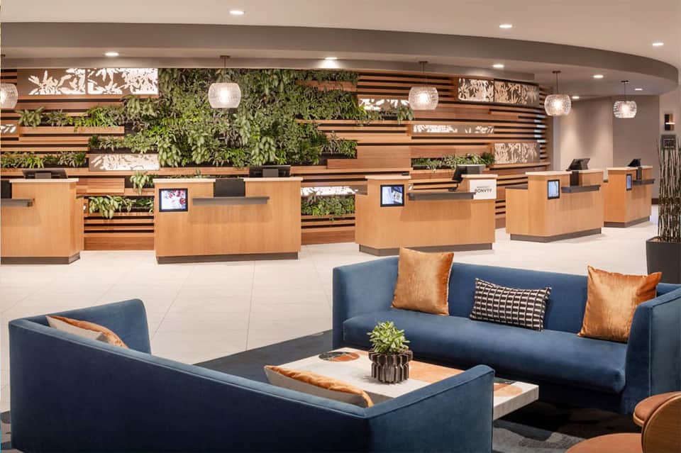 Modern hotel lobby with living green wall, wooden accents, and blue seating