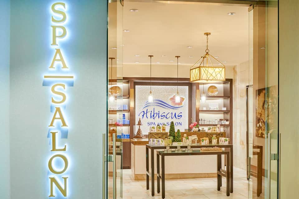 Spa salon entrance with gold neon sign and elegant interior displaying Hibiscus branding