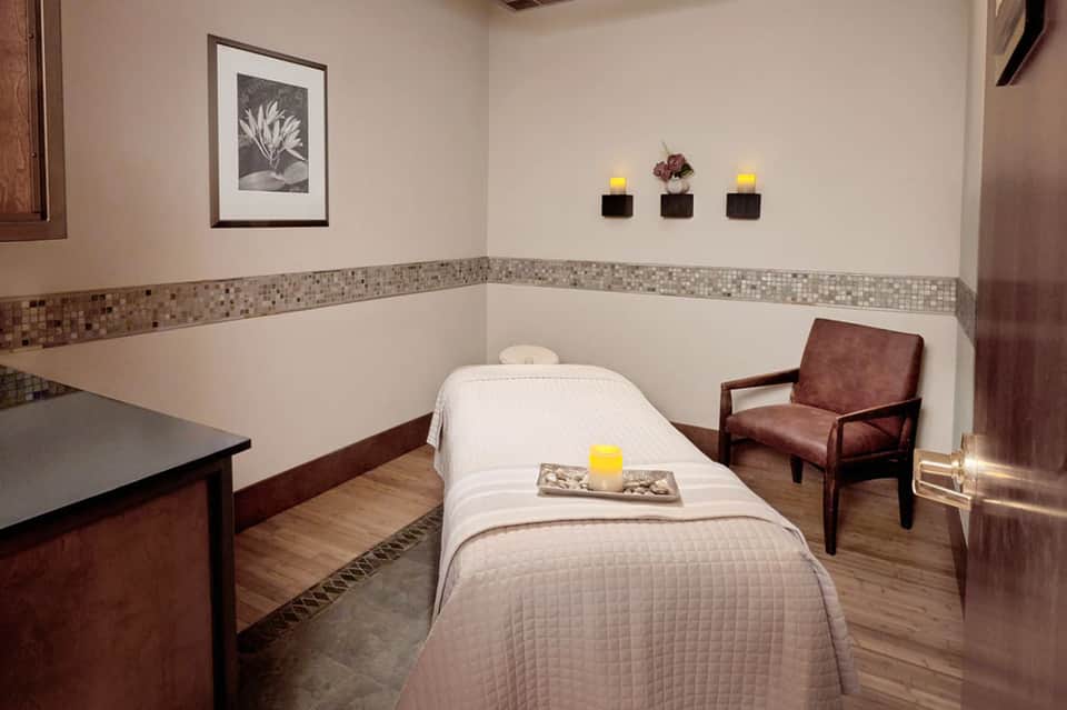 Spa treatment room with massage table, wood accents, and calming neutral decor