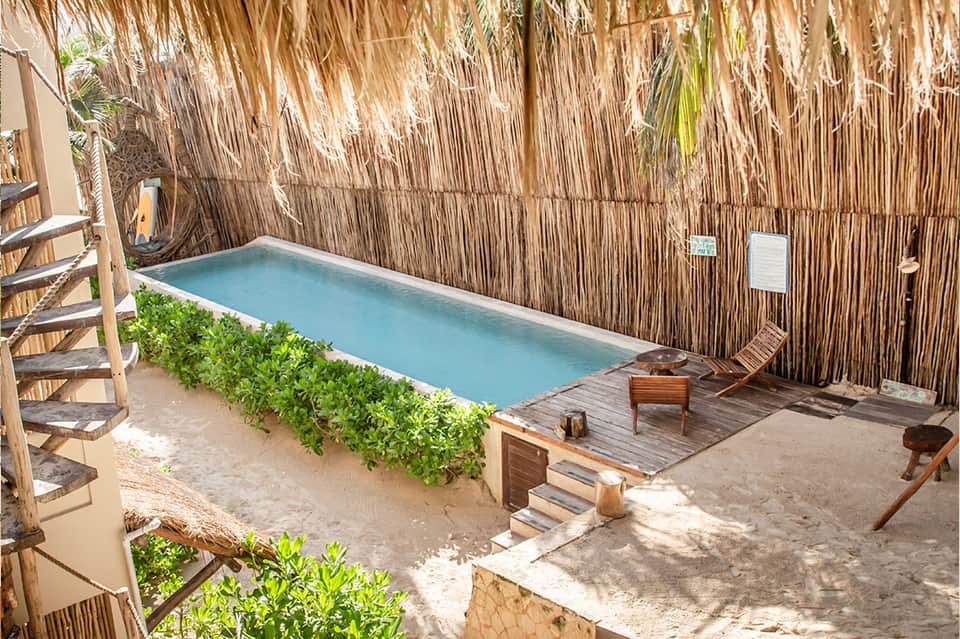 Tropical private pool surrounded by thatched palapa roof and wooden deck