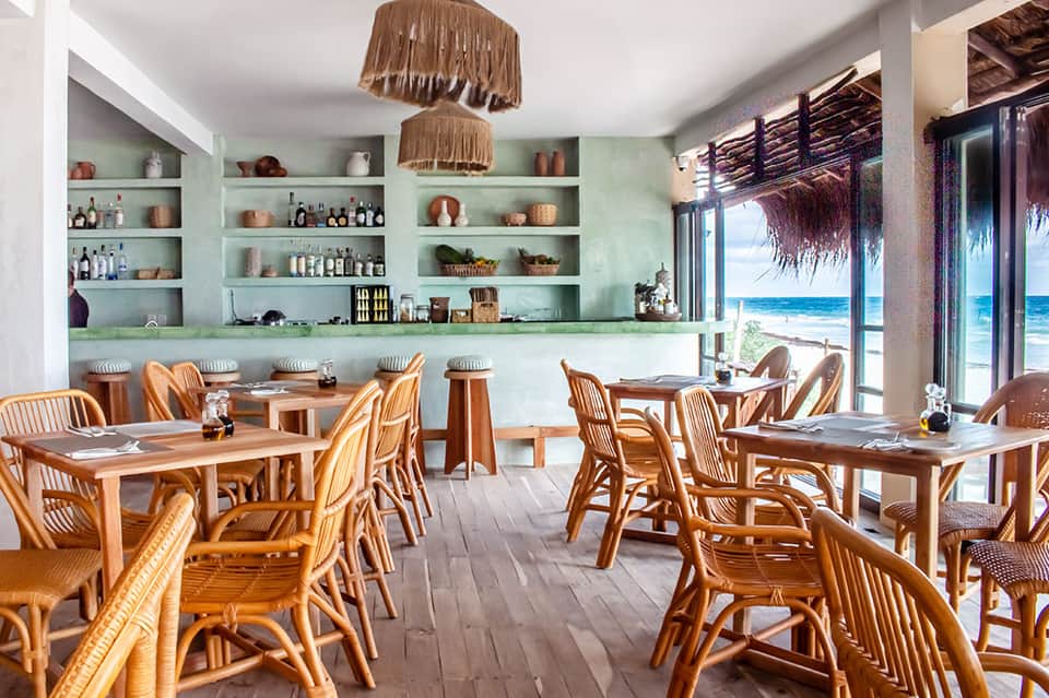 Beachfront restaurant with turquoise walls, wooden furniture, and ocean view