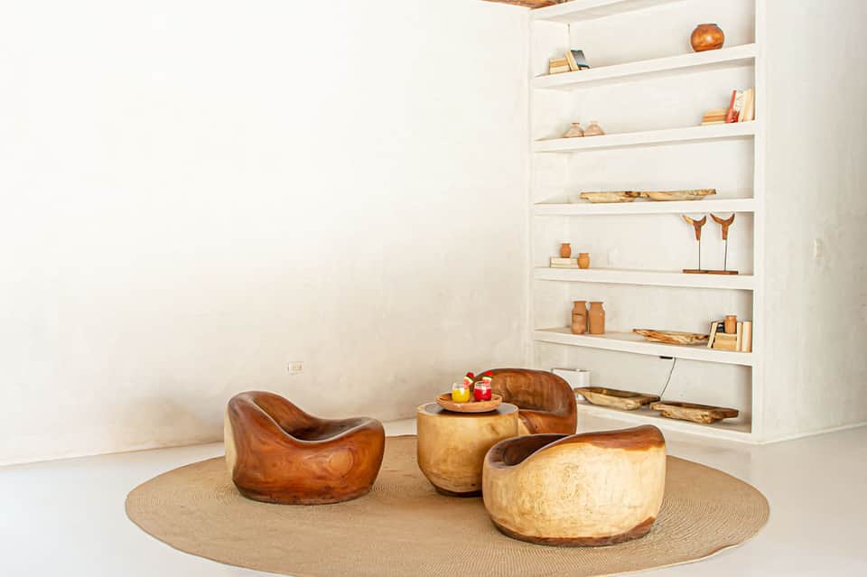 Contemporary lounge with wooden sculptural chairs and shelving displaying decorative objects