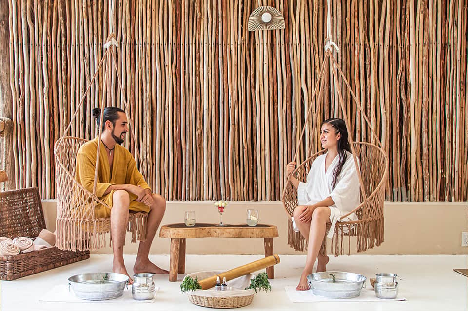 Spa couple sitting in woven chairs before an herbal treatment session