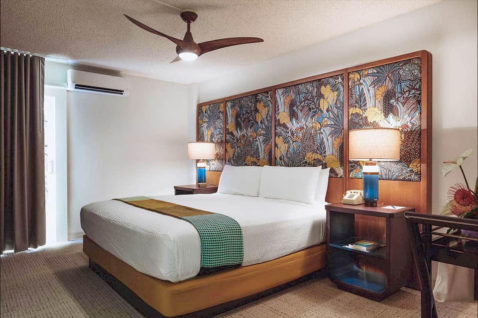 Upscale hotel bedroom with wood headboard, white bedding, and artistic wall panel