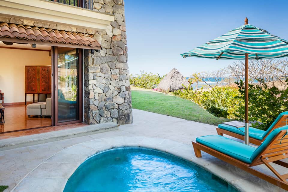 Luxury home with private pool, turquoise lounge chairs, stone patio, and ocean water view