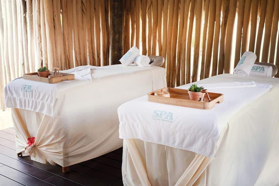 Outdoor spa treatment cabanas with white linens and wooden accents on beach deck