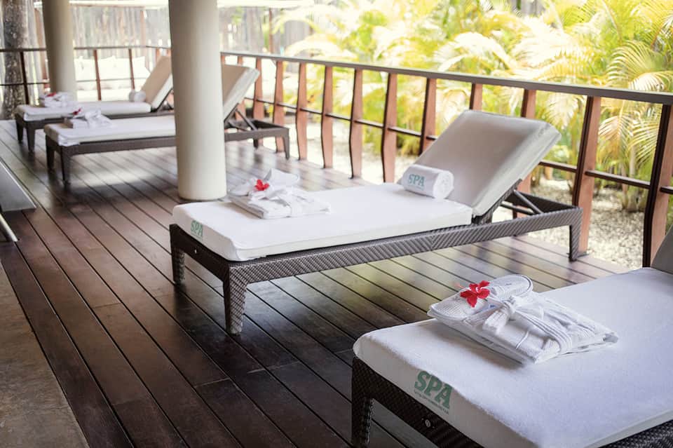 Spa deck with lounge chairs, towels, and tropical vegetation overlooking the ocean