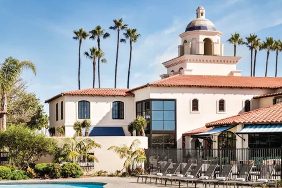 Spanish colonial-style resort building with dome, palm trees, and pool