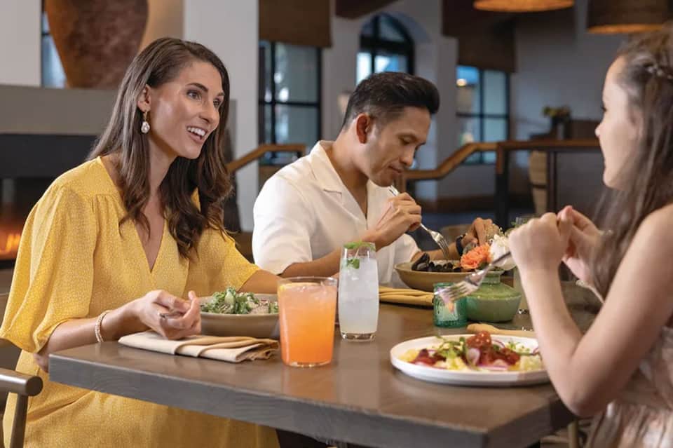 Three guests dining together at restaurant with salads and beverages in modern interior