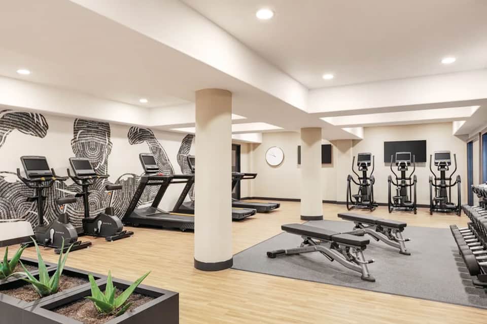 Modern hotel fitness center with cardio equipment, ellipticals, treadmills, and geometric wall art