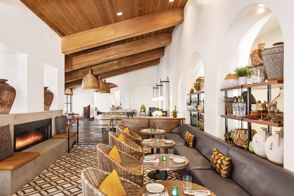 Contemporary restaurant interior with arched ceilings, fireplace, wooden beams, and table seating