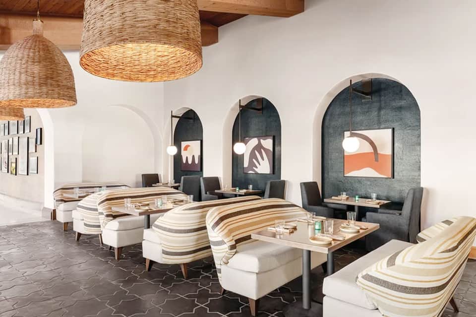 Modern lounge interior with striped seating, woven pendant lights, and arched wall niches
