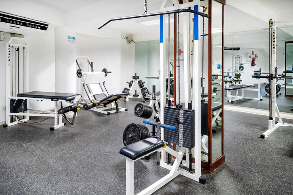 Modern gym facility with weight machines, dumbbells, benches, and mirrored walls