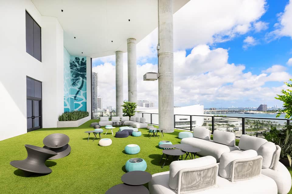 Rooftop terrace with artificial grass, modern white seating, city skyline and waterfront views