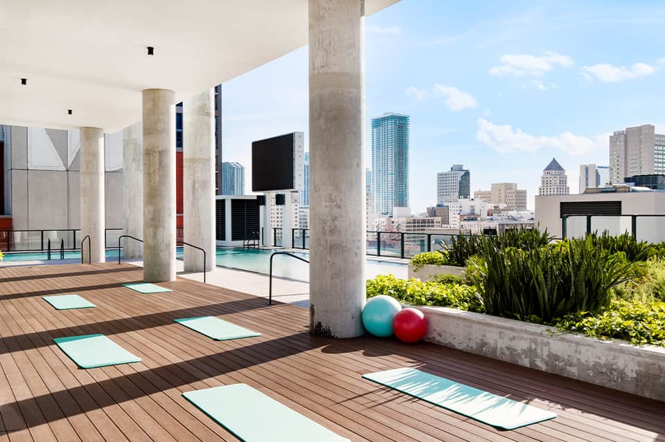 Rooftop yoga and fitness deck with city skyline views, exercise mats, and pool