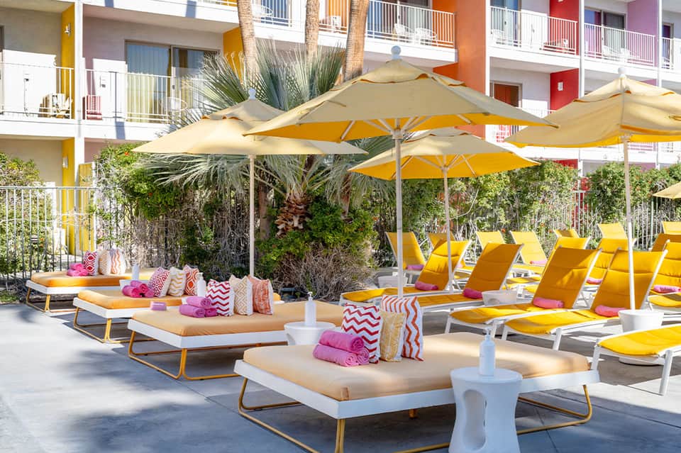 Luxury resort pool deck with yellow umbrellas, lounge chairs, and colorful decor