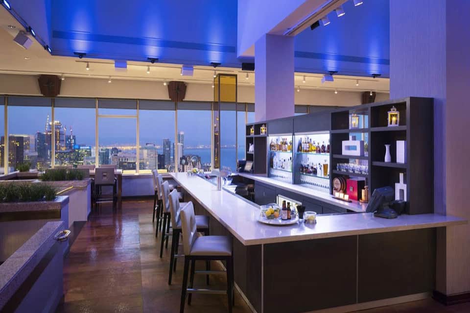 Contemporary bar lounge with purple lighting and expansive city skyline views