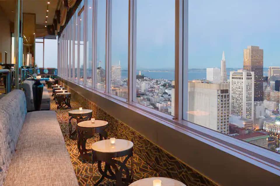 High-rise hotel bar with floor-to-ceiling windows overlooking city skyline