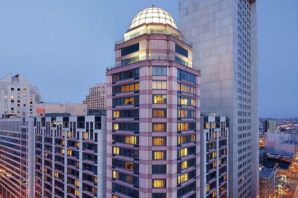 Pink and purple art deco hotel tower with curved architecture and illuminated windows at dusk