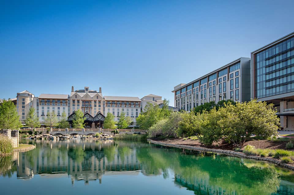 Waterfront hotel buildings reflected in calm canal with green landscaping
