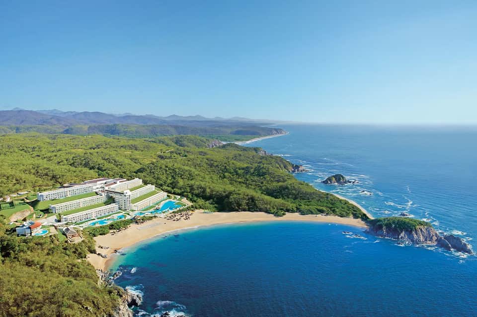 Cliffside resort overlooking a sandy beach cove and blue ocean water