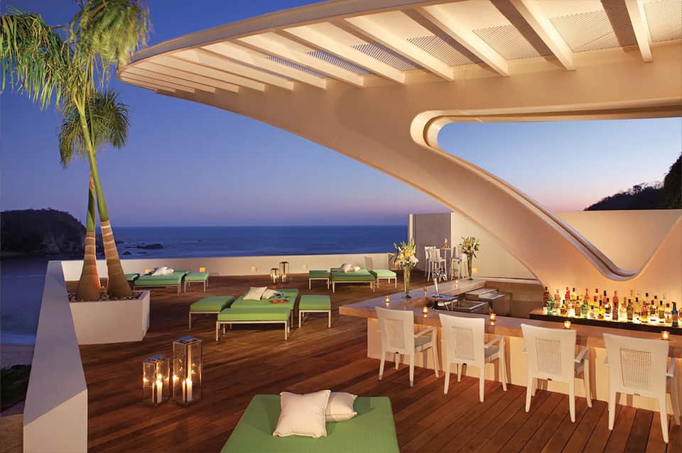 Luxury clifftop bar lounge with curved white architecture, ocean views, and modern furnishings
