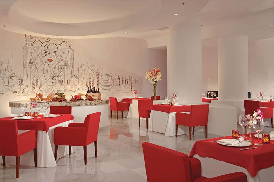 Elegant red and white dining room with decorative wall art and flower centerpieces