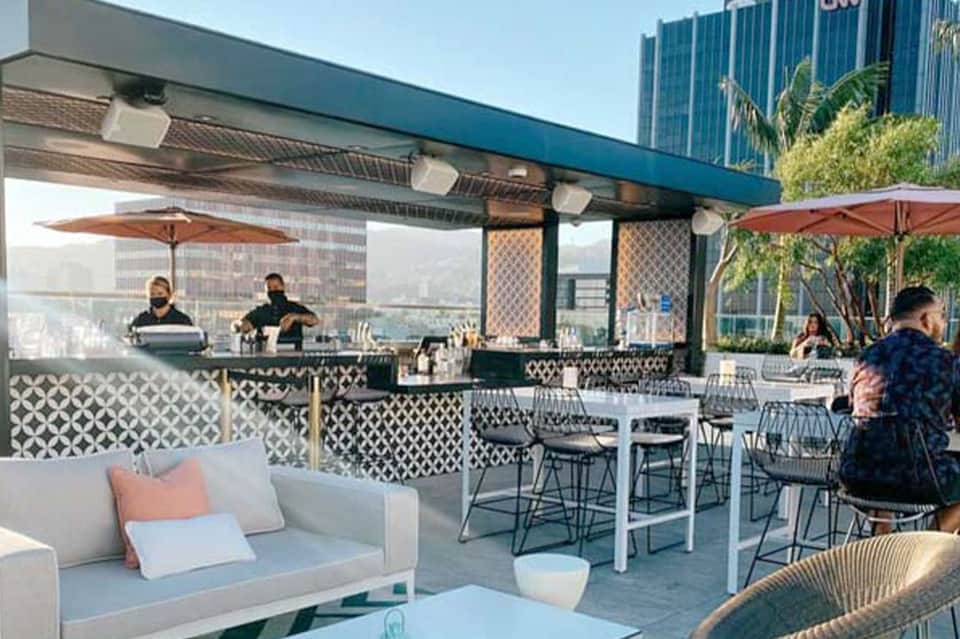 Urban rooftop bar and lounge with patterned screens, umbrellas, and city skyline views