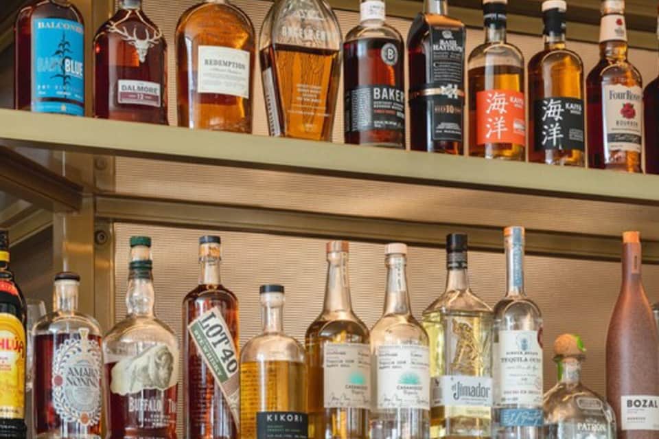 Shelves displaying collection of premium spirits including whiskey, rum, and tequila bottles