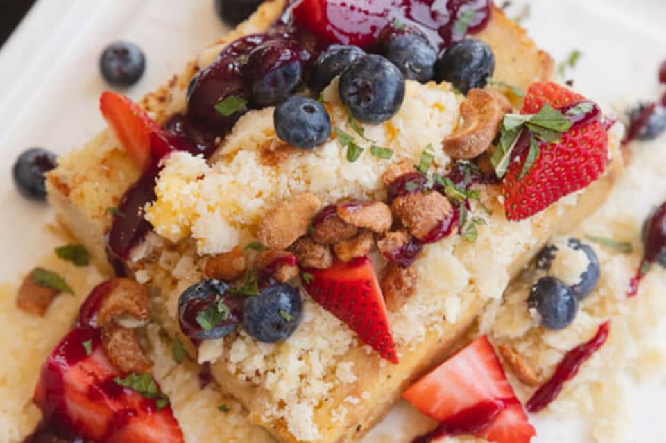 Gourmet dessert plate with berries, coconut, and whipped cream on brioche bread
