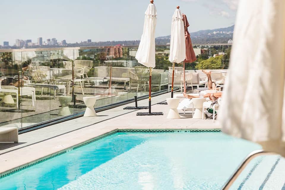 Rooftop pool with panoramic city views, white umbrellas, and lounge seating