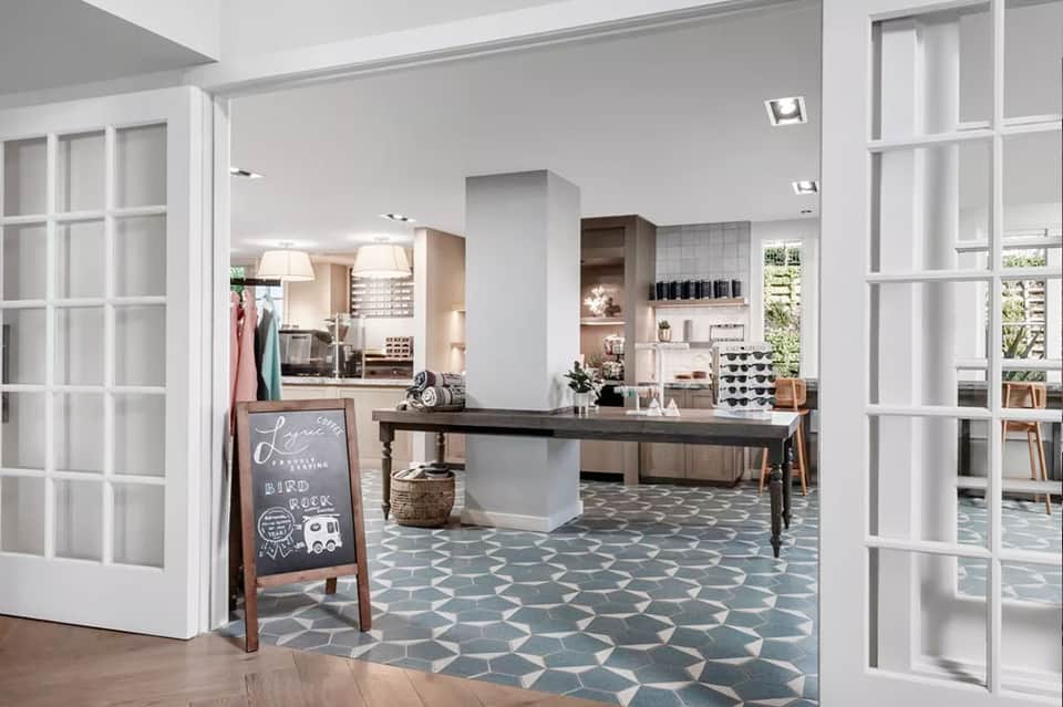 Spa and salon reception area with modern white doors, wooden desk, and geometric floor tiles