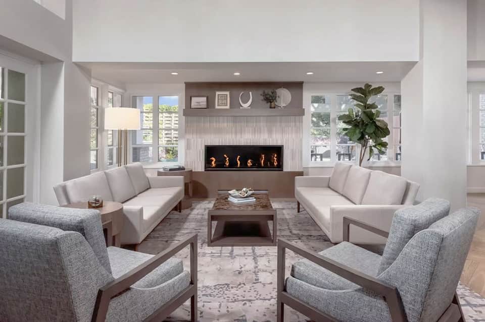 Contemporary living room with fireplace, neutral seating, and floor-to-ceiling windows